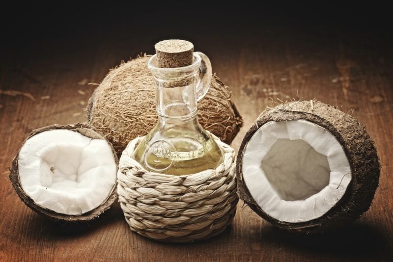 coconut oil and coconuts on wooden background