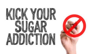 Hand with marker writing the word Kick Your Sugar Addiction