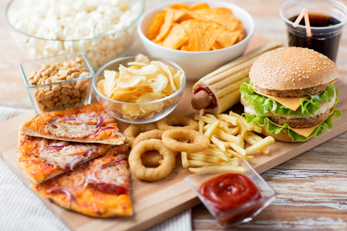 fast food and unhealthy eating concept - close up of fast food snacks and coca cola drink on wooden table