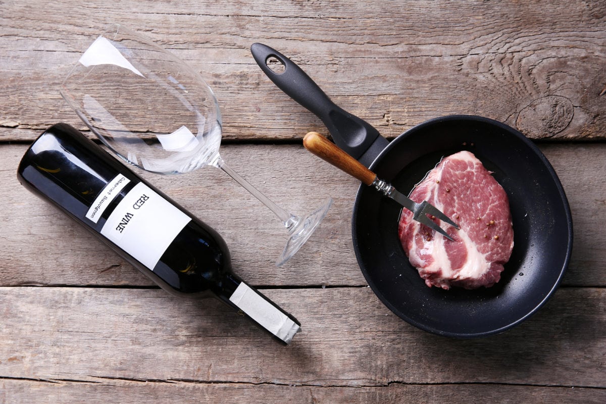 Marbled beef steak and wine bottle on wooden background