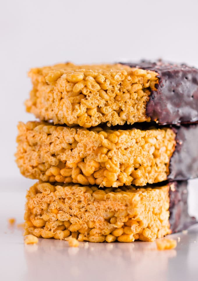 These healthy & no-bake vegan rice crispy treats are made with only 3 ingredients: peanut butter, maple syrup, and crispy rice cereal. No marshmallow here. Protein powder and chocolate topping are optional. This easy, clean eating snack can be whipped together in less than 10 minutes and is TOTALLY kid approved! :) | onecleverchef.com #glutenfree #dairyfree #veganprotein #proteinsnack #family #fun 