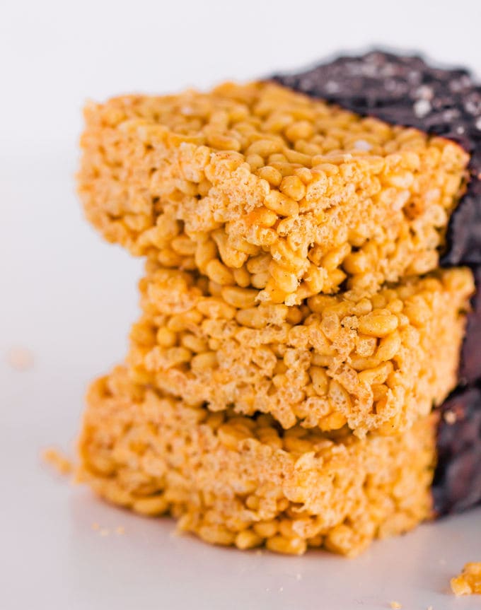 These healthy & no-bake vegan rice crispy treats are made with only 3 ingredients: peanut butter, maple syrup, and crispy rice cereal. No marshmallow here. Protein powder and chocolate topping are optional. This easy, clean eating snack can be whipped together in less than 10 minutes and is TOTALLY kid approved! :) | onecleverchef.com #glutenfree #dairyfree #veganprotein #proteinsnack #family #fun 