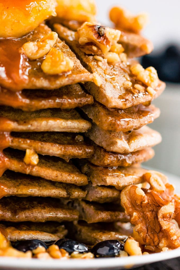 These healthy & fluffy vegan buckwheat pancakes are very easy to make. Only 4 ingredients, no eggs, dairy-free and gluten-free, these are topped with caramelized banana slices, blueberries, a peanut butter caramel coulis, walnuts and maple syrup for a sweet & savory breakfast. | onecleverchef.com #onecleverchef #breakfast #vegan #glutenfree 