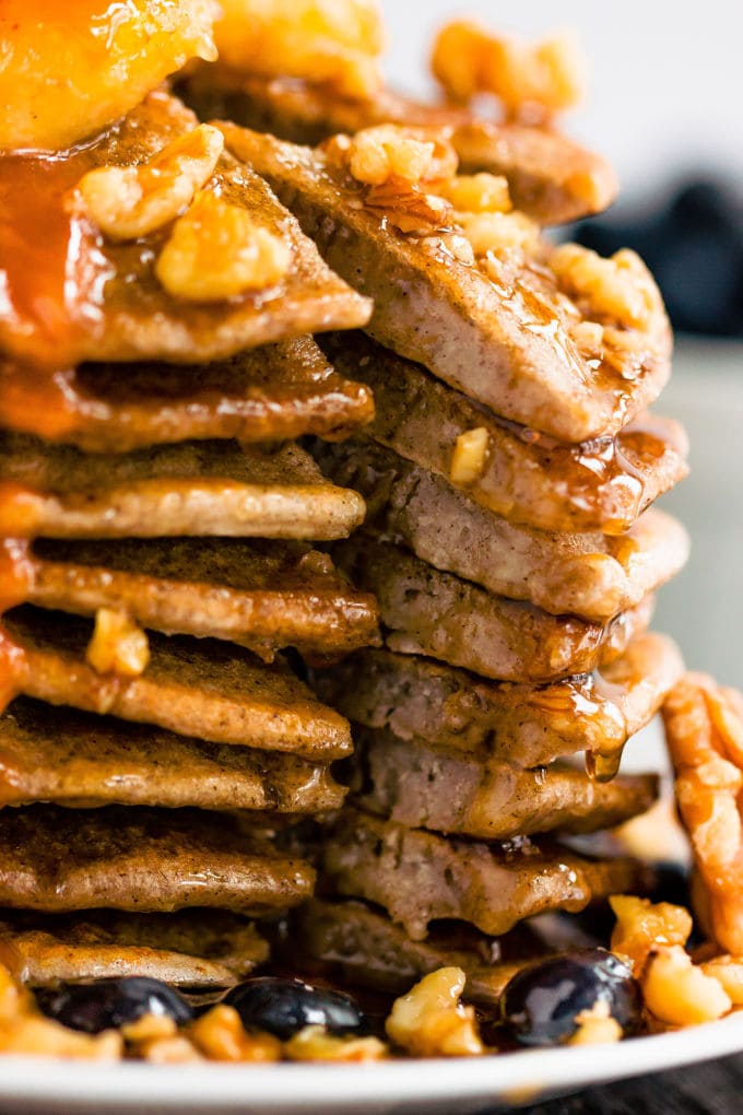 These healthy & fluffy vegan buckwheat pancakes are very easy to make. Only 4 ingredients, no eggs, dairy-free and gluten-free, these are topped with caramelized banana slices, blueberries, a peanut butter caramel coulis, walnuts and maple syrup for a sweet & savory breakfast. | onecleverchef.com #onecleverchef #breakfast #vegan #glutenfree 