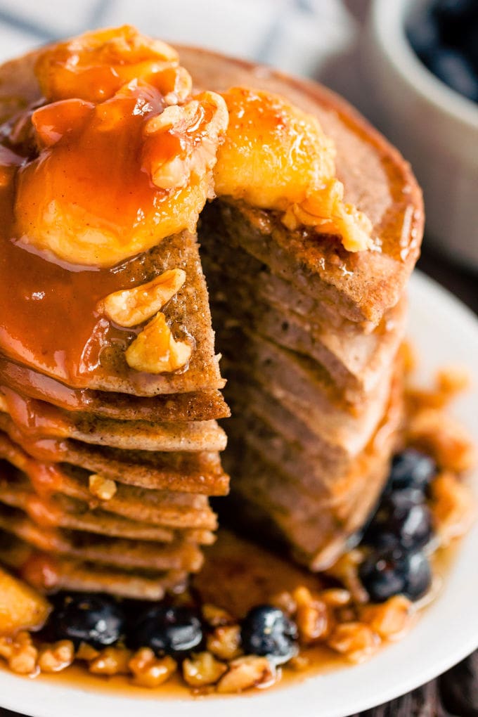 These healthy & fluffy vegan buckwheat pancakes are very easy to make. Only 4 ingredients, no eggs, dairy-free and gluten-free, these are topped with caramelized banana slices, blueberries, a peanut butter caramel coulis, walnuts and maple syrup for a sweet & savory breakfast. | onecleverchef.com #onecleverchef #breakfast #vegan #glutenfree 