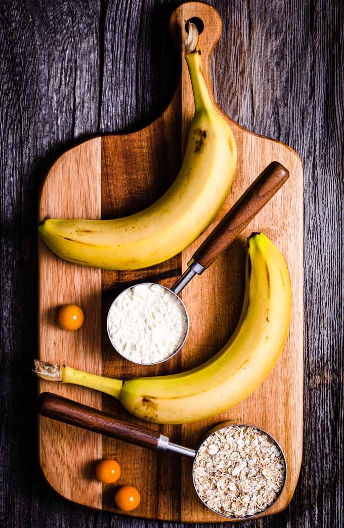 Bananas, oatmeal and vanilla protein powder on a wooden plank.