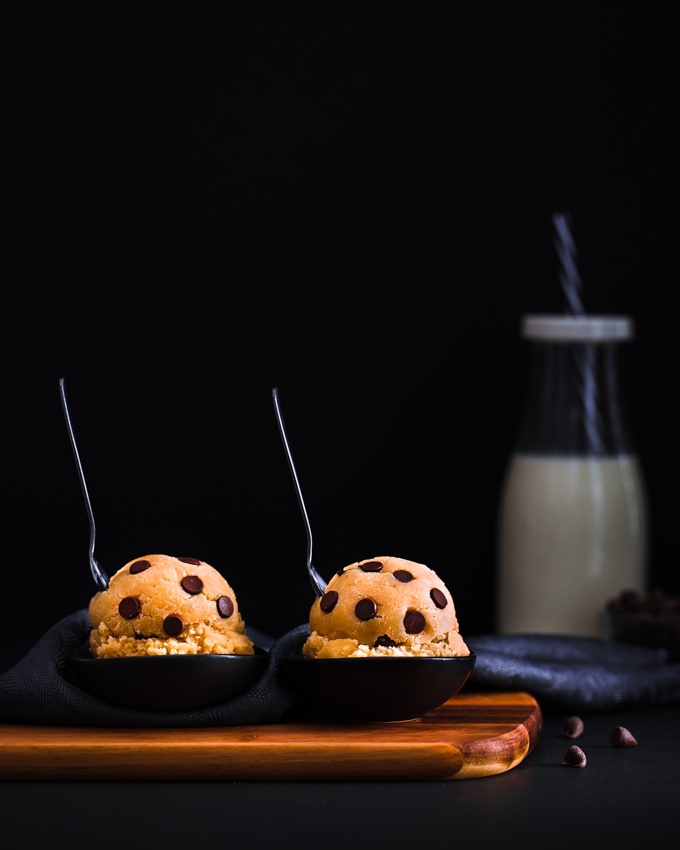 2 Edible cookie dough balls on a wooden board.