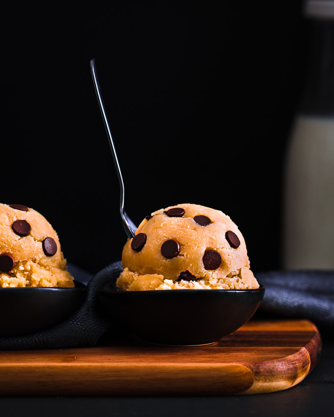 2 Edible cookie dough balls on a wooden board.